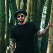 Man Holding Bamboo Plant Wearing Sunglasses and Fedora Hat