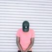 Man Wearing Pink Tee Shirt Leaning on Wall While Head Down